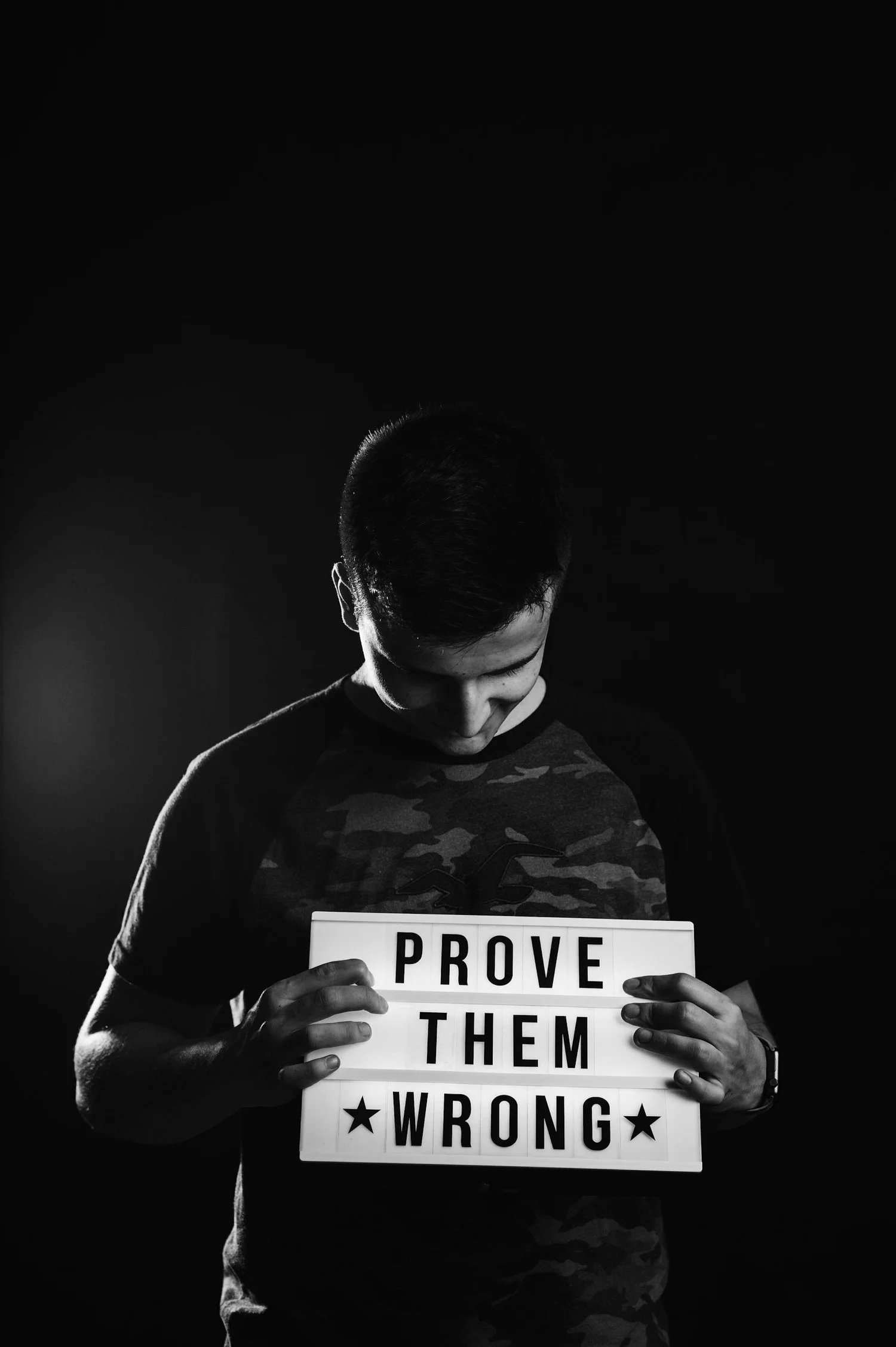 A man holding a lightbox sign that reads Prove Them Wrong